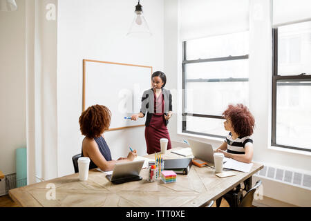 Confident businesswoman explaining strategy to female colleagues in board room Stock Photo