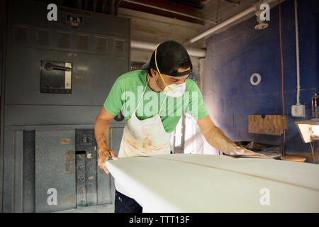 worker shaping surfboard in workshop Stock Photo