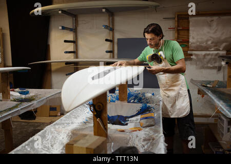worker measuring surfboard in workshop Stock Photo