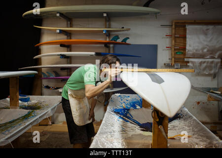 worker using ruler to measure surfboard in workshop Stock Photo