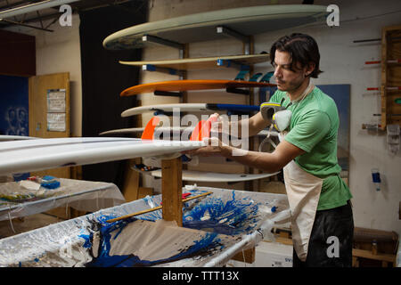 Concentrated worker making surfboard in workshop Stock Photo