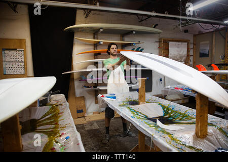 worker examining surfboard in workshop Stock Photo
