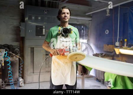 Portrait of male worker holding sander while standing in workshop Stock Photo