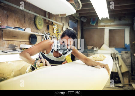 Woman shaping surfboard in workshop Stock Photo