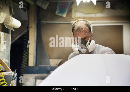 Craftsperson examining surfboard in workshop Stock Photo