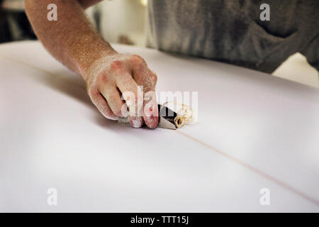 Close-up of hand shaping surfboard in workshop Stock Photo