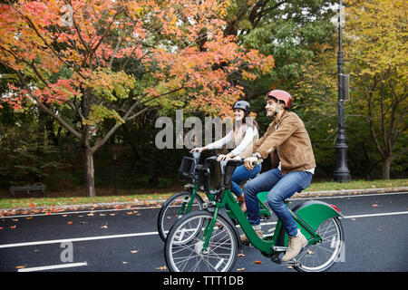 Smiling couple riding bicycle at park Stock Photo