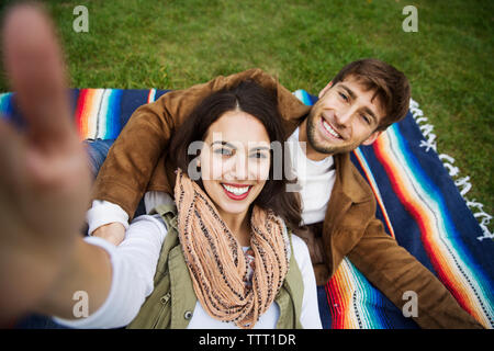 Portrait of happy couple lying on blanket at park Stock Photo