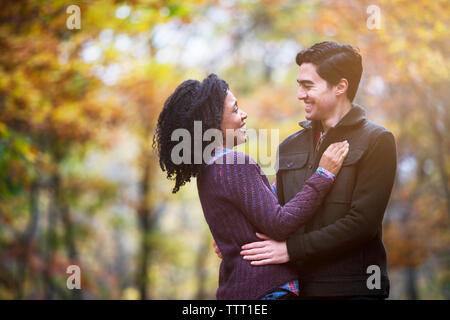 Happy couple looking at each other while standing in forest Stock Photo