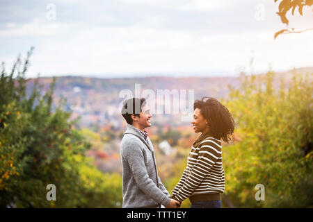 Loving couple looking at each other while standing in orchard against sky Stock Photo