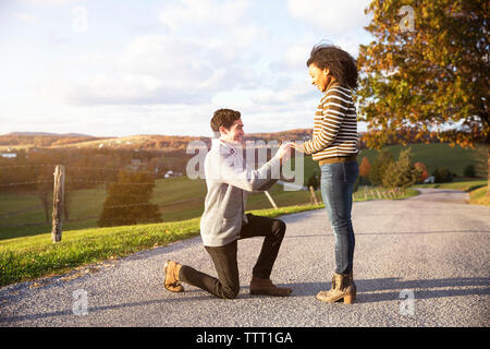 Man proposing happy girlfriend on footpath Stock Photo