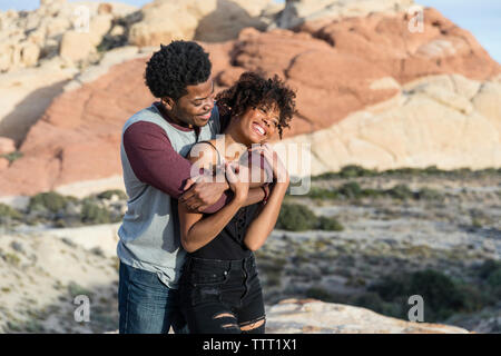 Romantic couple standing against rock formation Stock Photo
