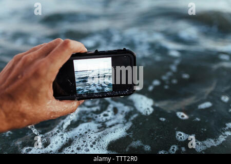 Cropped hand photographing sea Stock Photo
