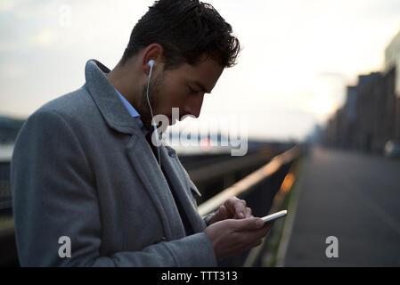 businessman using mobile phone while standing against railing Stock Photo