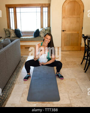 Cheerful mother carrying daughter while exercising at home Stock Photo
