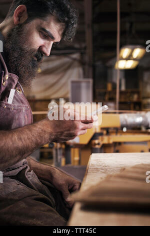 Side view of manual worker using phone at workshop Stock Photo