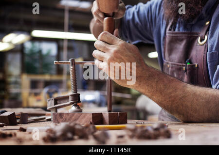 Cropped image of worker hammering tools in plank at wood shop Stock Photo