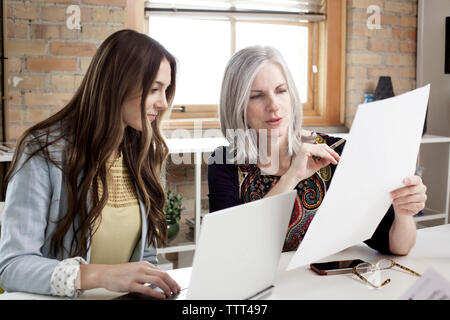 Mature female manager explaining plan to executive in creative office Stock Photo