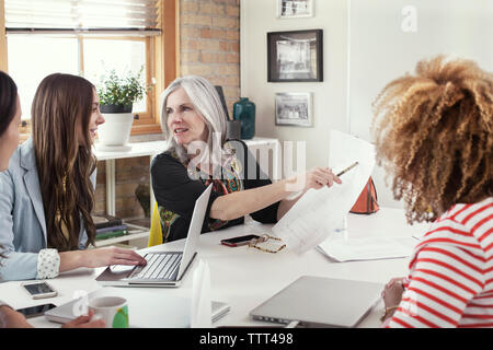 Mature businesswoman explaining strategy to female executives in board room Stock Photo