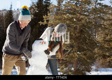 Happy siblings making snowman Stock Photo