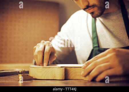 Cropped image of worker examining violin in workshop Stock Photo