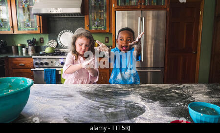 Boy displaying his mess with girl in the kitchen Stock Photo