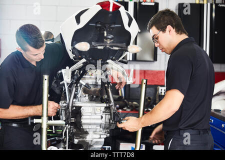 workers examining motorbike in workshop Stock Photo