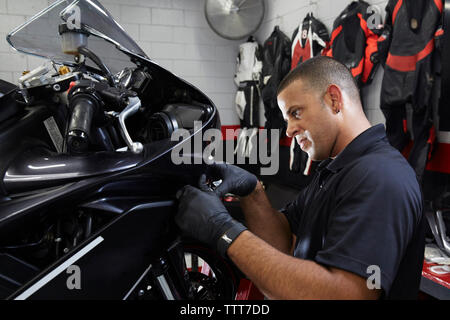 Confident worker examining motorbike in workshop Stock Photo