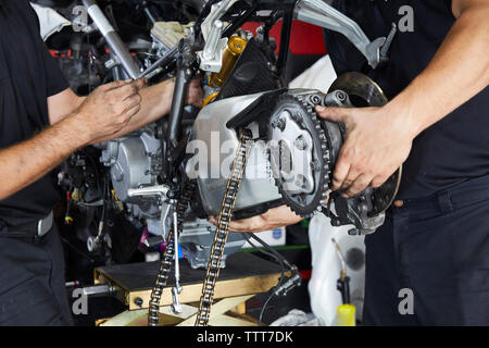 Midsection of workers making motorbike in workshop Stock Photo