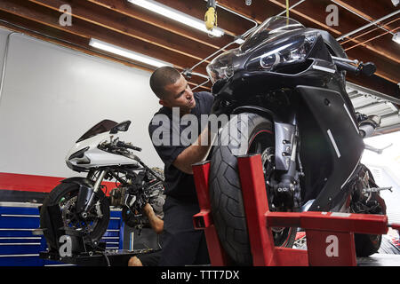 Confident worker working on motorbike in factory Stock Photo