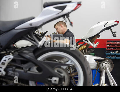 Side view of worker repairing motorbike in workshop Stock Photo