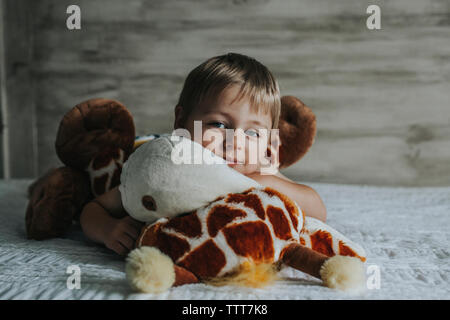 Portrait of boy playing with stuffed toys on bed at home Stock Photo