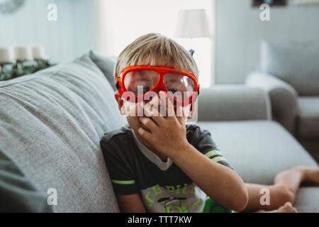 Portrait of boy wearing eyewear while sitting on sofa at home Stock Photo