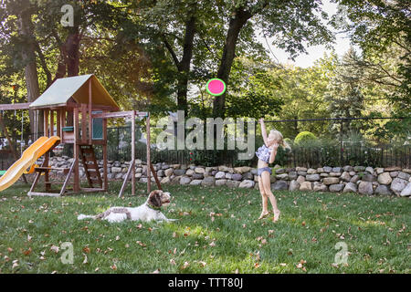 Playful girl throwing frisbee with dog at playground Stock Photo