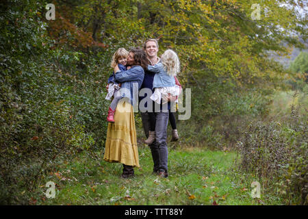 family of four happy together in wooded clearing during fall
