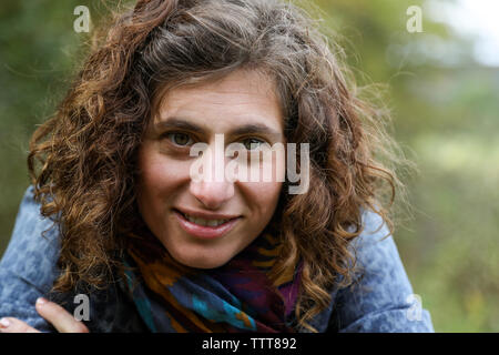 close up of woman with curly brown hair wearing scarf