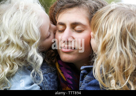 mom being kissed on cheeks by daughters close up Stock Photo
