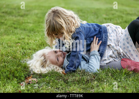 two sisters laying on the grass laughing and playing together Stock Photo