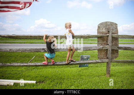 two girls hanging on wooden fence on farm Stock Photo