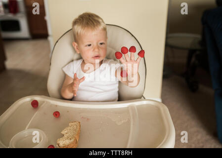 Smiling baby boy looking through window while standing in crib at home Stock Photo