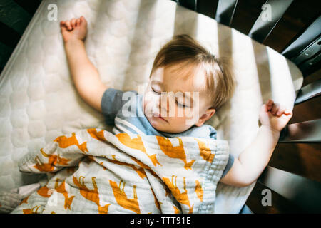 Overhead view of cute baby boy sleeping in crib at home Stock Photo