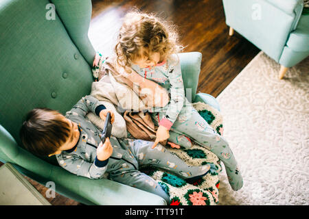 High angle view of siblings sitting on chair at home Stock Photo