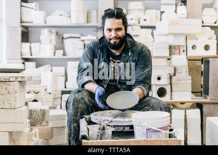 Portrait of craftsman showing earthenware in workshop Stock Photo