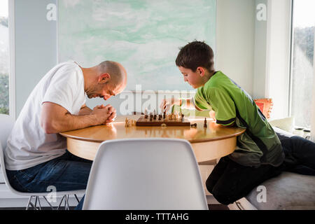 Father with son playing chess on table at home Stock Photo