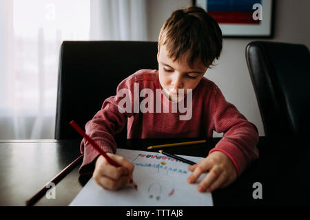 Boy drawing with colored pencil on paper at home Stock Photo