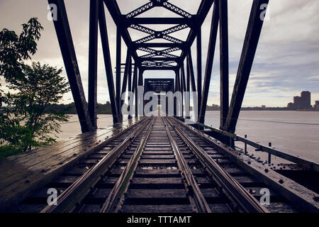 Railway bridge over river against cloudy sky Stock Photo