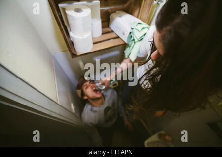 High angle view of woman feeding drinking water to man in bathroom Stock Photo