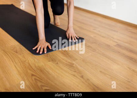 Woman Placing Exercise Mat On Hardwood Floor In Yoga Class Stock