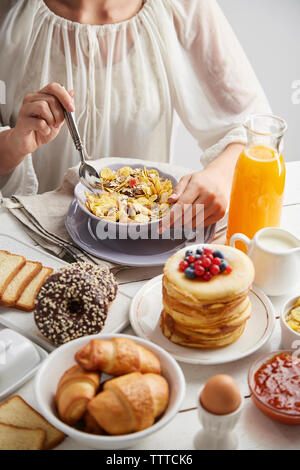 Midsection of woman having breakfast on table at home Stock Photo