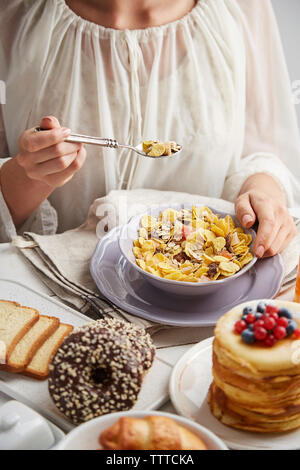 Midsection of woman eating breakfast on table at home Stock Photo